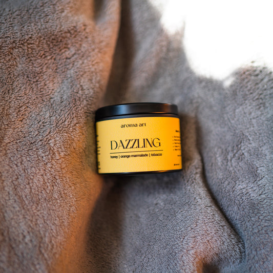 3.5oz travel sized tin crackling wooden wick candle named Dazzling with notes of honey, orange marmalade, and tobacco. A blaze for the senses, perfect for a decadent moment.